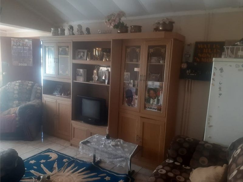 A living room featuring built-in wooden cabinetry and tiled flooring, offering a functional space with potential for modernization.