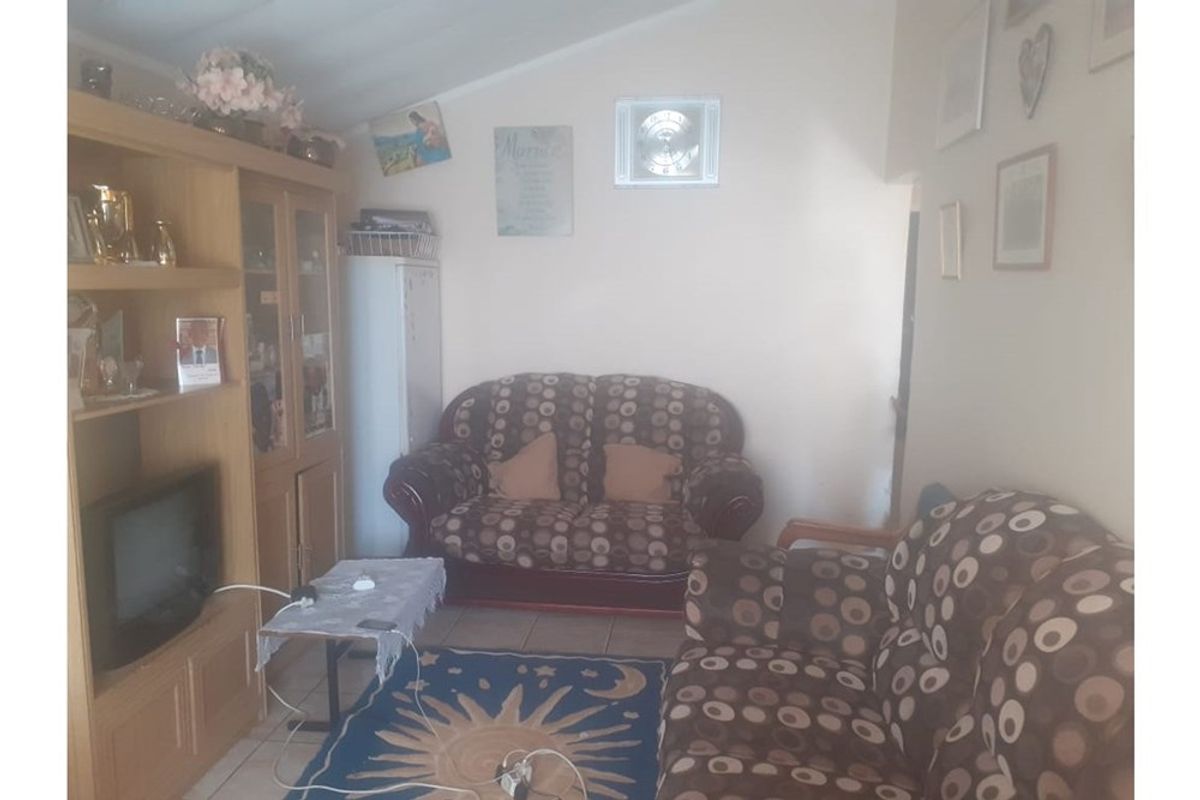 A living room area featuring tiled flooring and a sloped ceiling, providing a functional space for relaxation.