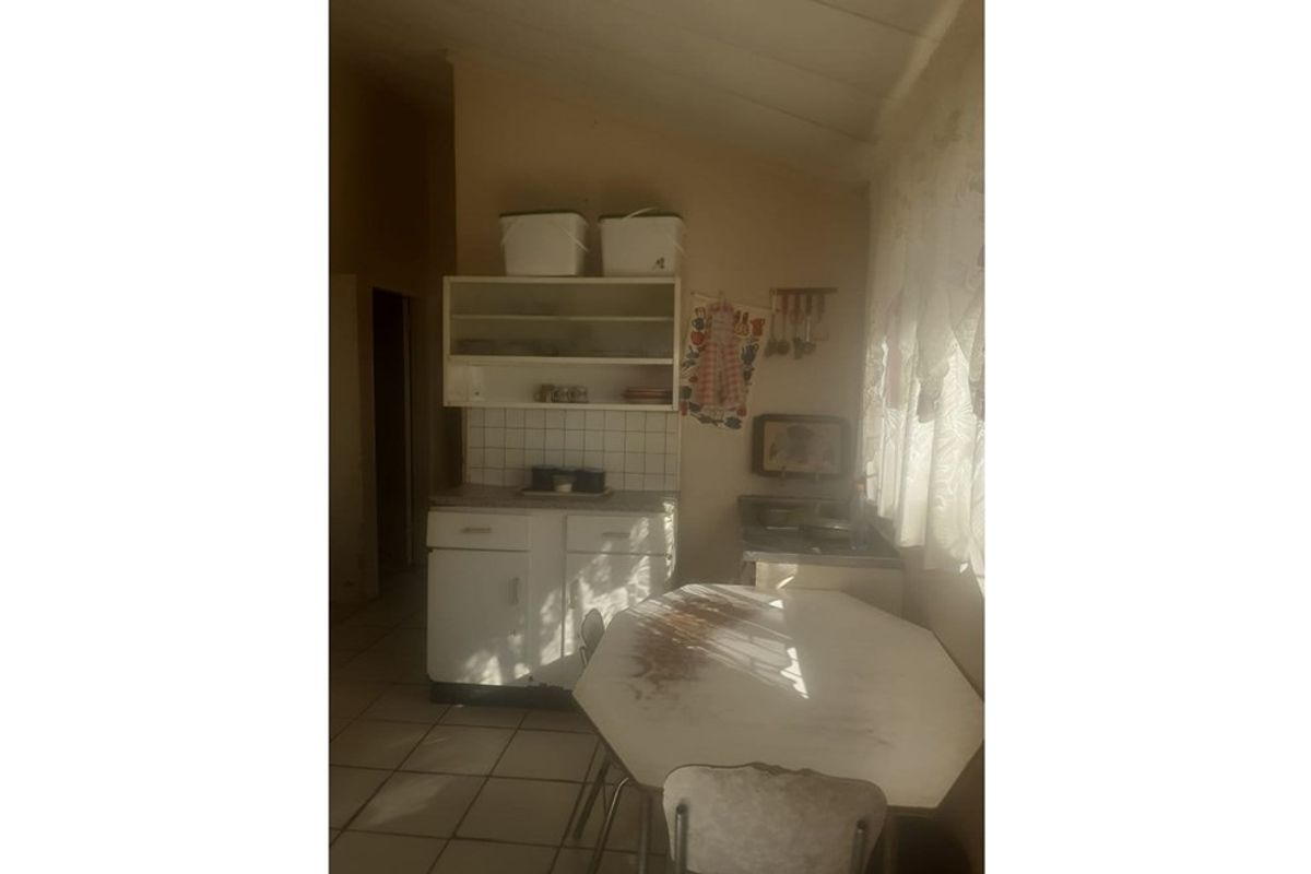 A dated kitchen area featuring built-in cabinetry, tiled splashbacks, and tiled flooring, offering potential for modernization and renovation.