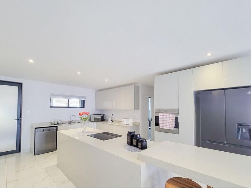 Modern kitchen featuring a central island with integrated cooktop, sleek cabinetry, quartz countertops, and high-quality built-in appliances in a bright, open-plan layout.