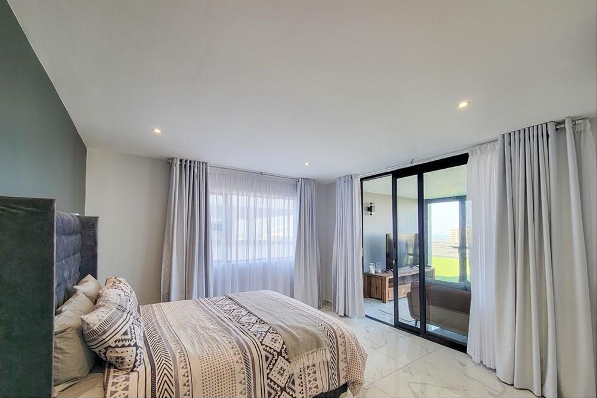 Spacious bedroom featuring modern marble-look floor tiles, recessed downlighting, and large sliding glass doors providing seamless access to the balcony.