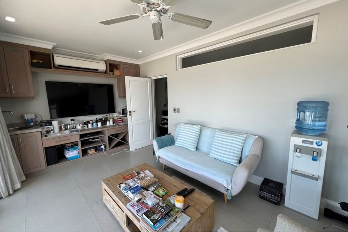 A living room featuring built-in cabinetry, a ceiling fan, and a split-system air conditioning unit.