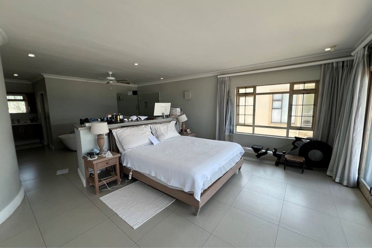Spacious open-plan bedroom featuring large windows, tiled flooring, recessed lighting, and an integrated en-suite bathroom area with a freestanding bathtub.