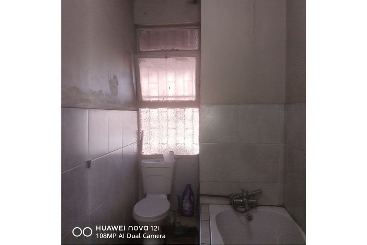 A dated bathroom featuring a standard toilet and bathtub, requiring renovation and cosmetic updates to improve the overall condition and aesthetic appeal.