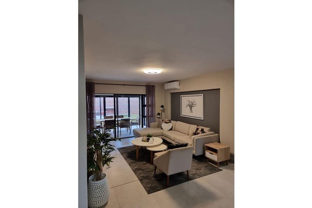 A well-maintained living room featuring tiled floors, a split-system air conditioner, and large sliding glass doors leading to an outdoor patio area.