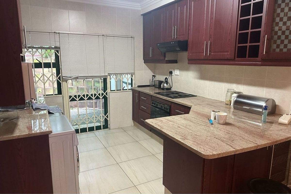 A functional kitchen featuring dark wood cabinetry, granite countertops, built-in appliances, and direct access to an outdoor area through a security gate.