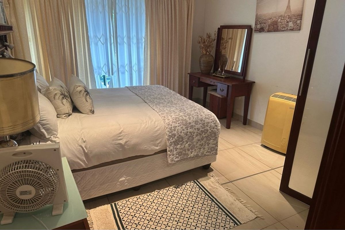 A bedroom featuring tiled flooring, a built-in wardrobe, and a sliding glass door providing access to the exterior.