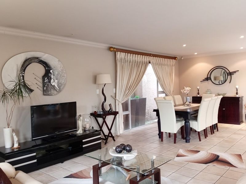 Spacious open-plan living and dining area featuring neutral wall tones, ceramic tiled flooring, and direct access to an outdoor space via sliding glass doors.