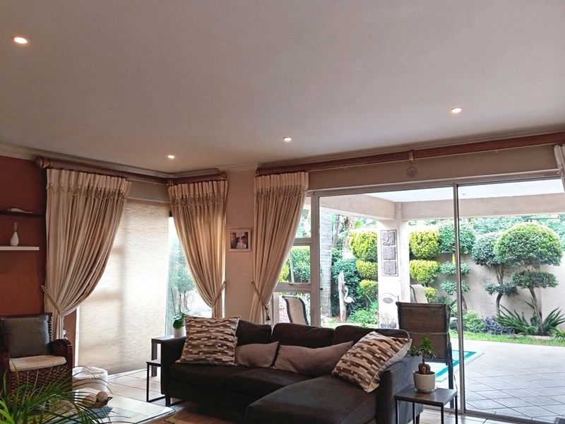 A comfortable living room featuring recessed downlights and large sliding glass doors that provide seamless access to the outdoor patio and garden area.