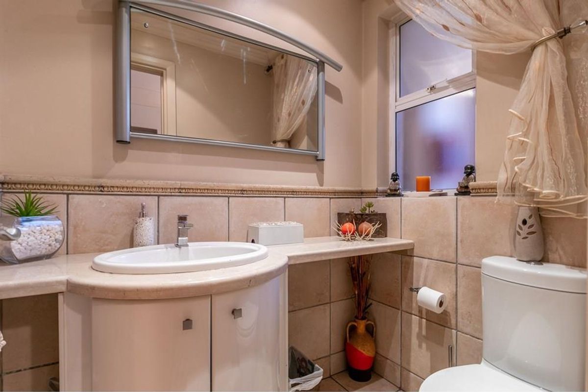 A functional bathroom featuring a vanity cabinet with a ceramic basin, tiled walls, and a toilet, offering a clean and practical layout.