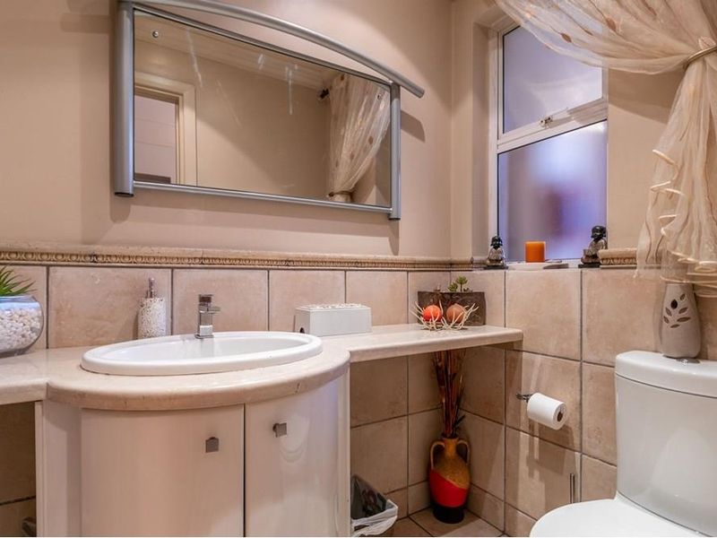 A functional bathroom featuring a vanity cabinet with a ceramic basin, tiled walls, and a toilet, offering a clean and practical layout.
