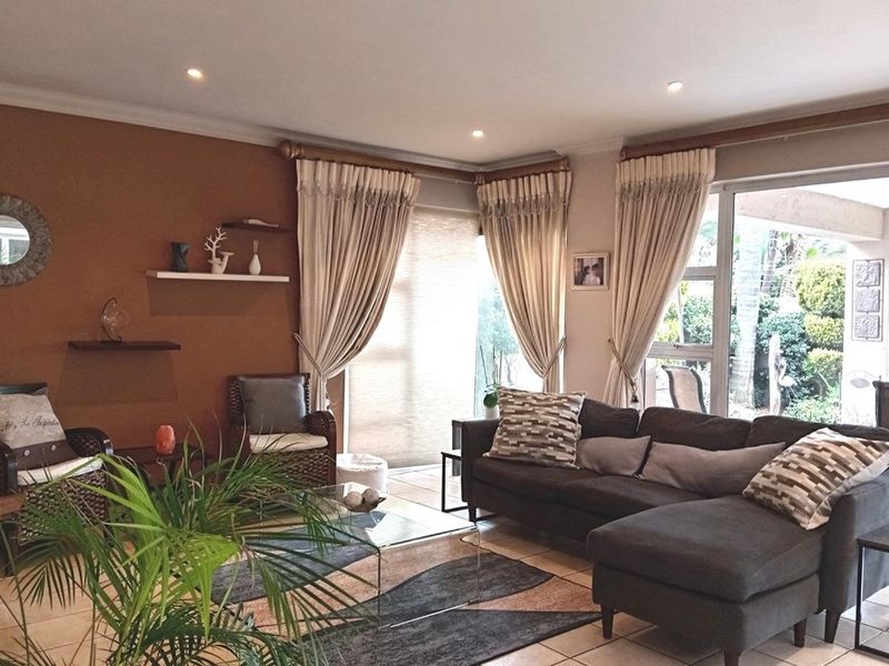 A comfortable living room featuring tiled flooring, recessed lighting, and large sliding glass doors that provide natural light and access to the outdoor area.