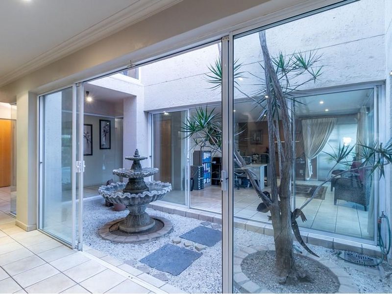 An enclosed central courtyard or atrium featuring a stone fountain, tiled flooring, and large sliding glass doors providing views into adjacent interior rooms.