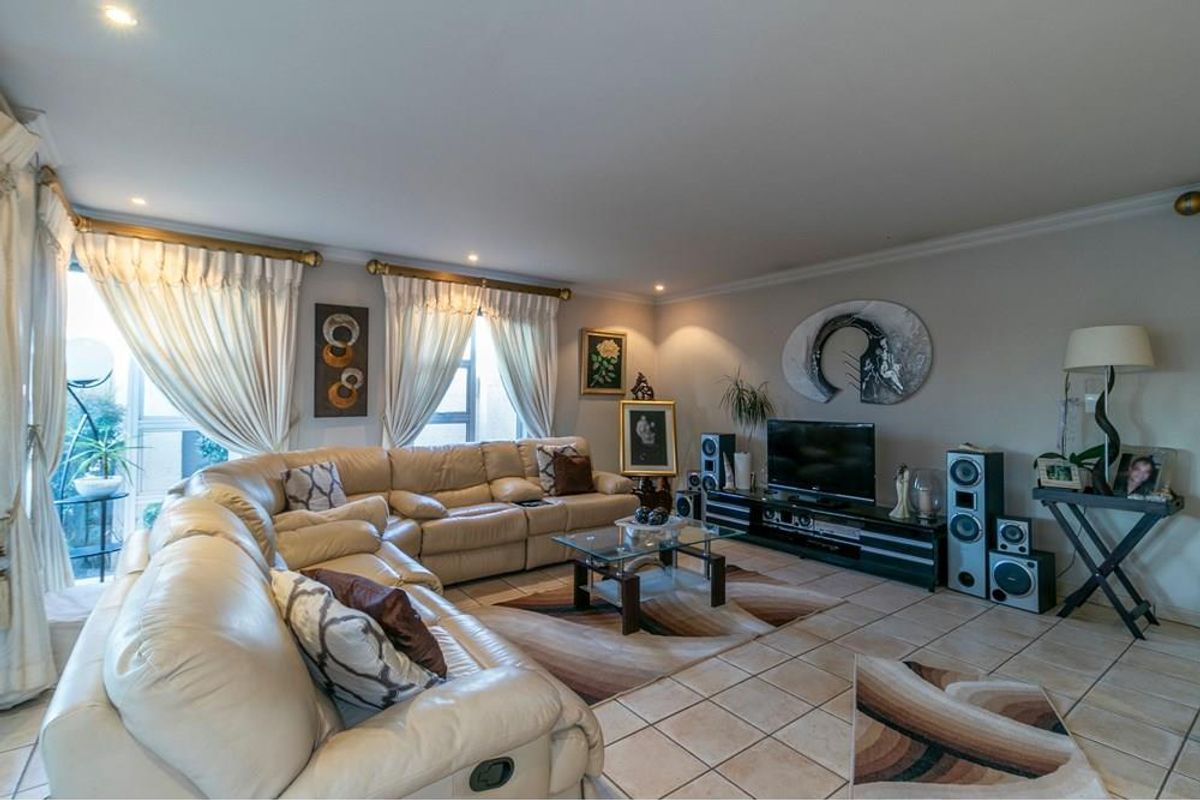 Spacious living room featuring ceramic floor tiles, recessed downlighting, and large sliding glass doors providing access to the exterior.