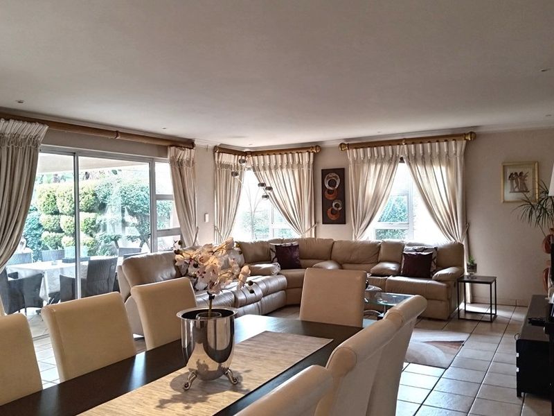 Spacious open-plan living and dining area featuring tiled flooring, recessed lighting, and large sliding glass doors providing access to the outdoor patio.