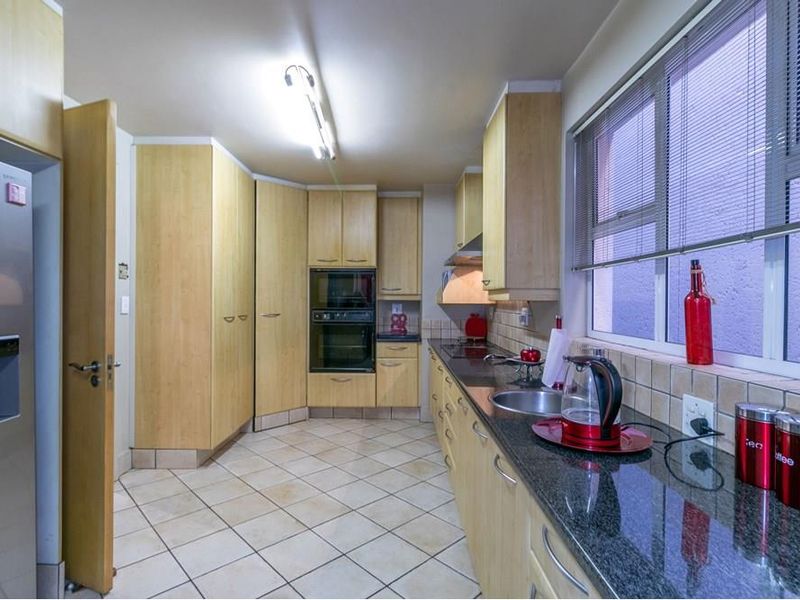 A functional kitchen featuring light wood cabinetry, granite countertops, a double wall oven, and tiled flooring with a neutral backsplash.