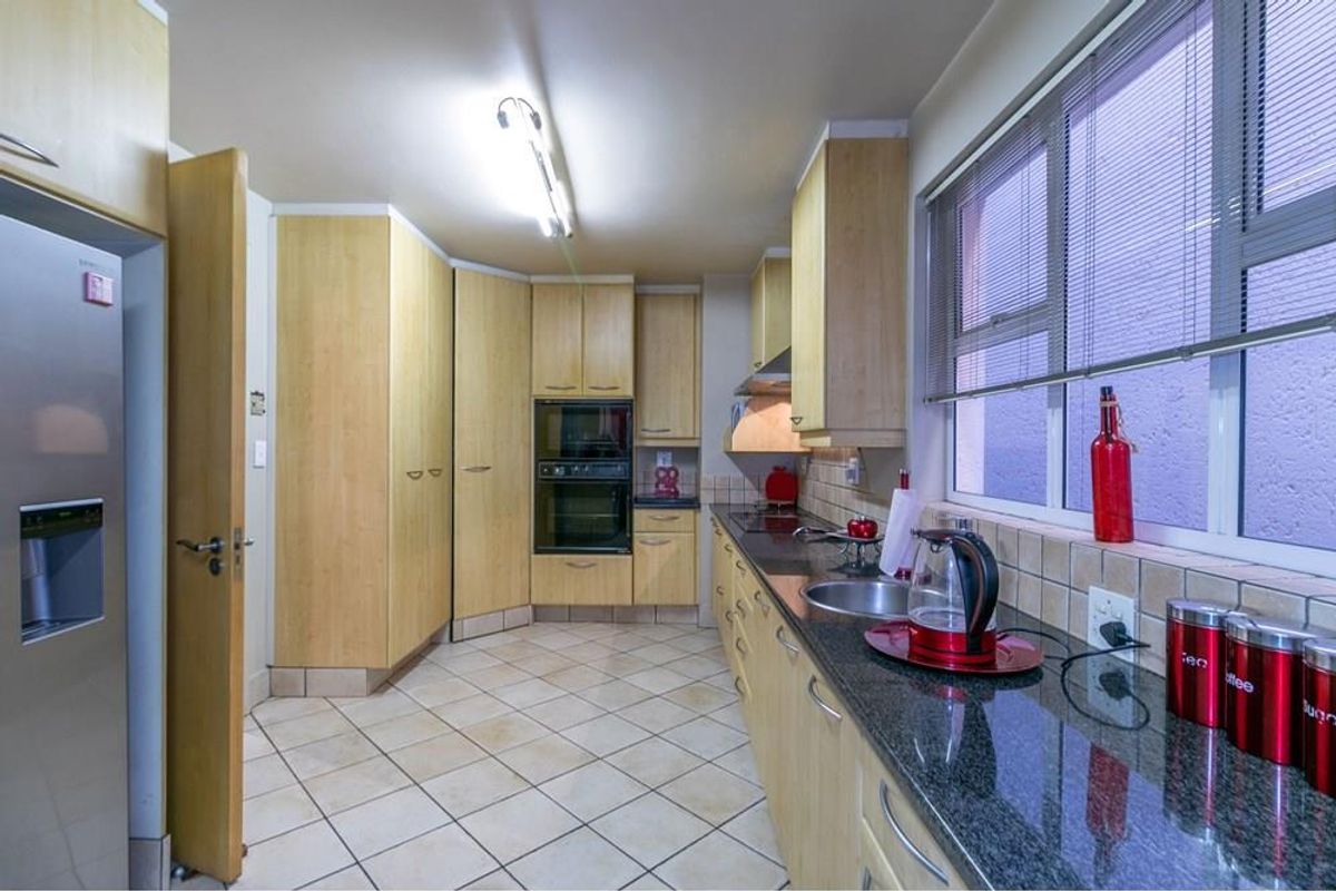A functional kitchen featuring light wood cabinetry, granite countertops, a double wall oven, and tiled flooring with a neutral backsplash.