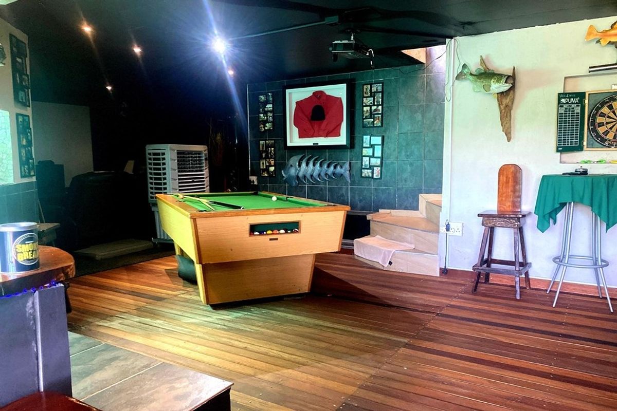 A multi-purpose entertainment area featuring hardwood flooring, a tiled feature wall, and integrated ceiling lighting, suitable for a games room or lounge.