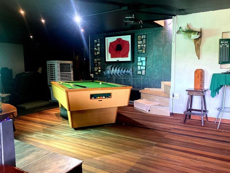 A multi-purpose entertainment area featuring hardwood flooring, a tiled feature wall, and integrated ceiling lighting, suitable for a games room or lounge.