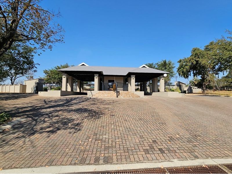 A well-maintained entrance gatehouse featuring a paved driveway, covered portico, and perimeter walling, providing a secure and professional access point to the property.