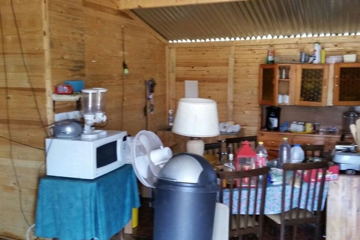 A rustic timber-walled kitchen area featuring basic cabinetry and a corrugated metal roof, suitable for a small holding or utility space.
