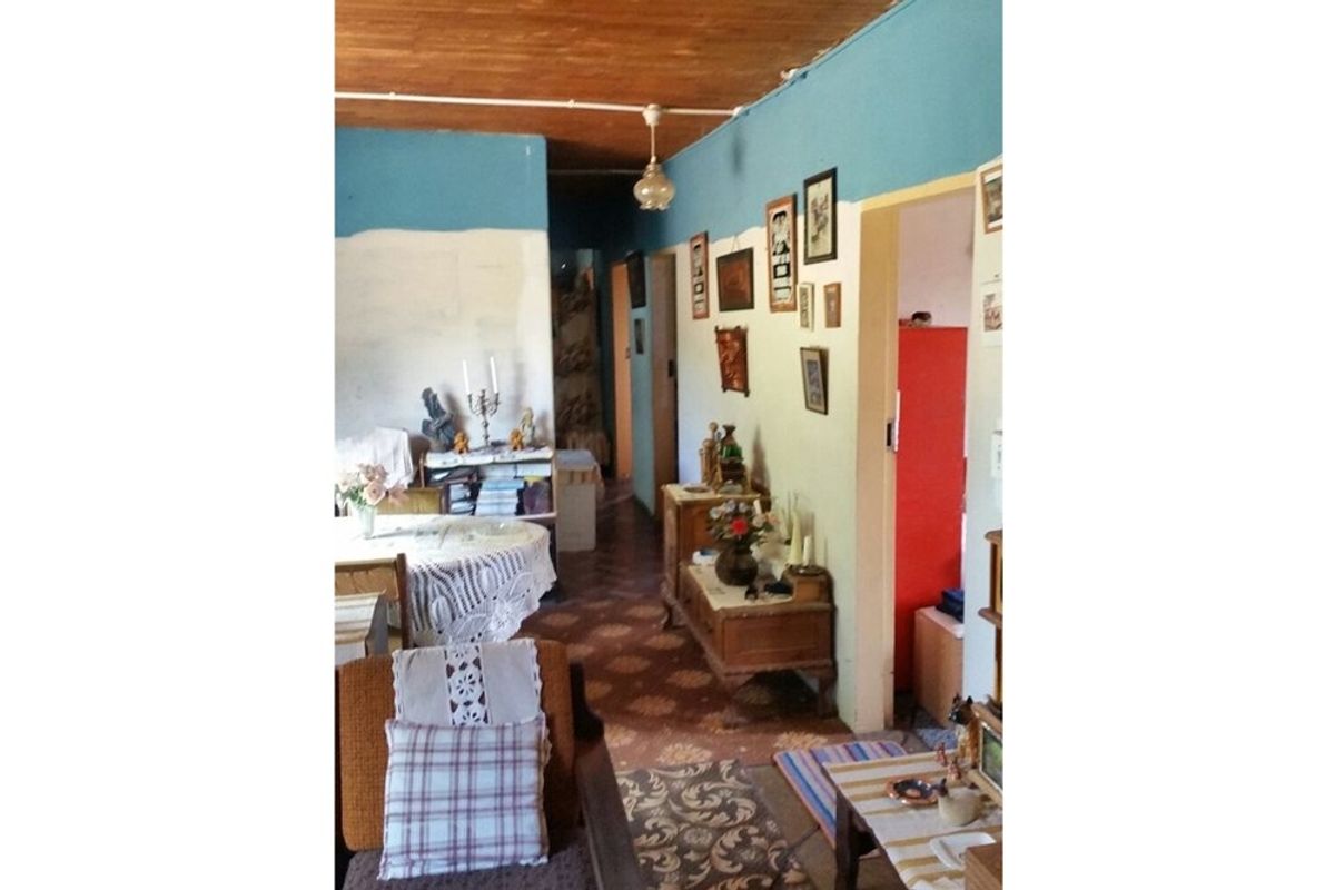 Interior view of a living area featuring a wooden ceiling, patterned flooring, and access to adjacent rooms.