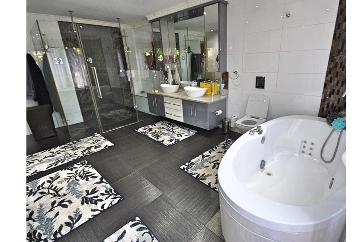 Modern bathroom featuring a large corner jetted bathtub, a glass-enclosed walk-in shower, and a double vanity with integrated mirror cabinetry.