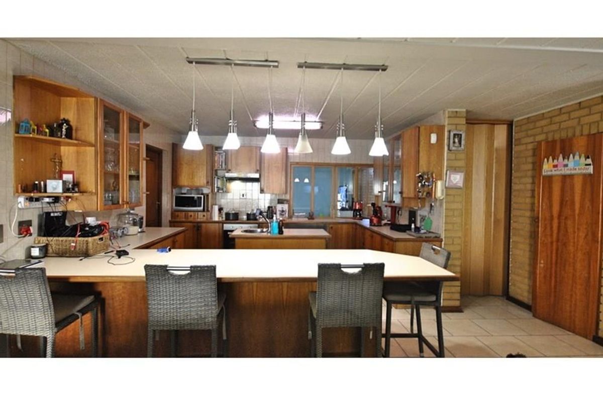 Spacious kitchen featuring extensive wooden cabinetry, a central island, breakfast bar seating, and tiled flooring, offering a functional layout for family living.