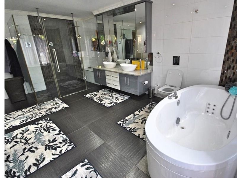 Modern bathroom featuring a large corner jetted bathtub, a glass-enclosed walk-in shower, and a double vanity with integrated mirror cabinetry.
