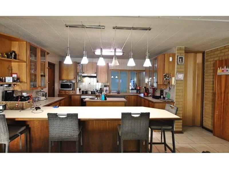 Spacious kitchen featuring extensive wooden cabinetry, a central island, breakfast bar seating, and tiled flooring, offering a functional layout for family living.