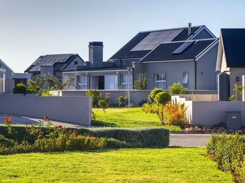 A well-maintained residential property exterior featuring a landscaped garden, paved driveway, solar energy infrastructure, and modern architectural design.