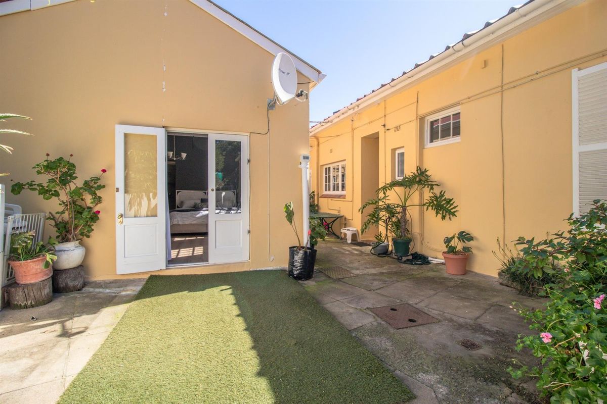A rear courtyard area featuring paved flooring, exterior wall access to the interior, and a satellite dish mounted on the building facade.