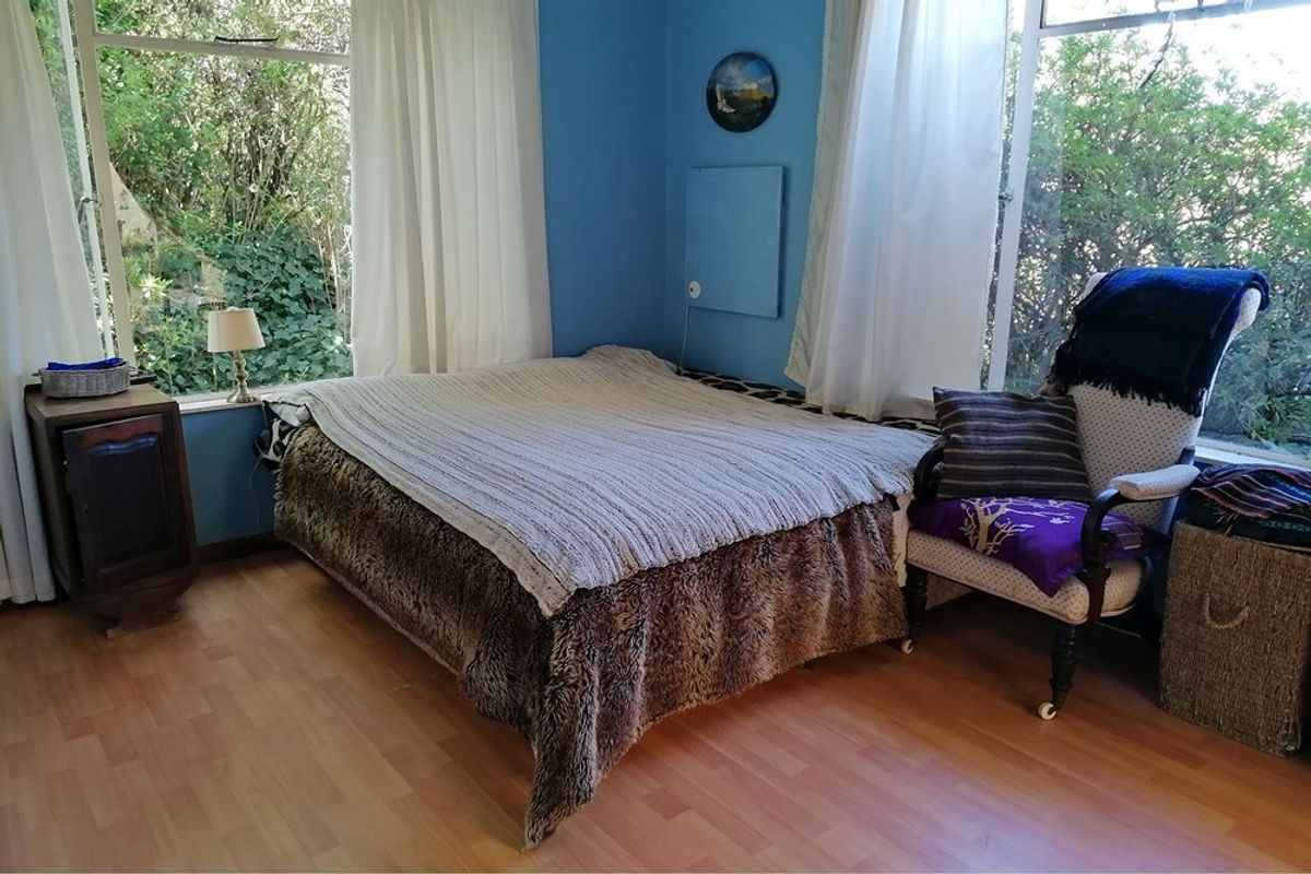 A bedroom featuring large windows that provide ample natural light and views of the surrounding greenery.
