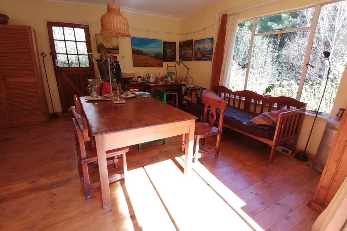 A rustic living area featuring warm timber flooring, large windows providing natural light, and a stable-style door leading to the exterior.