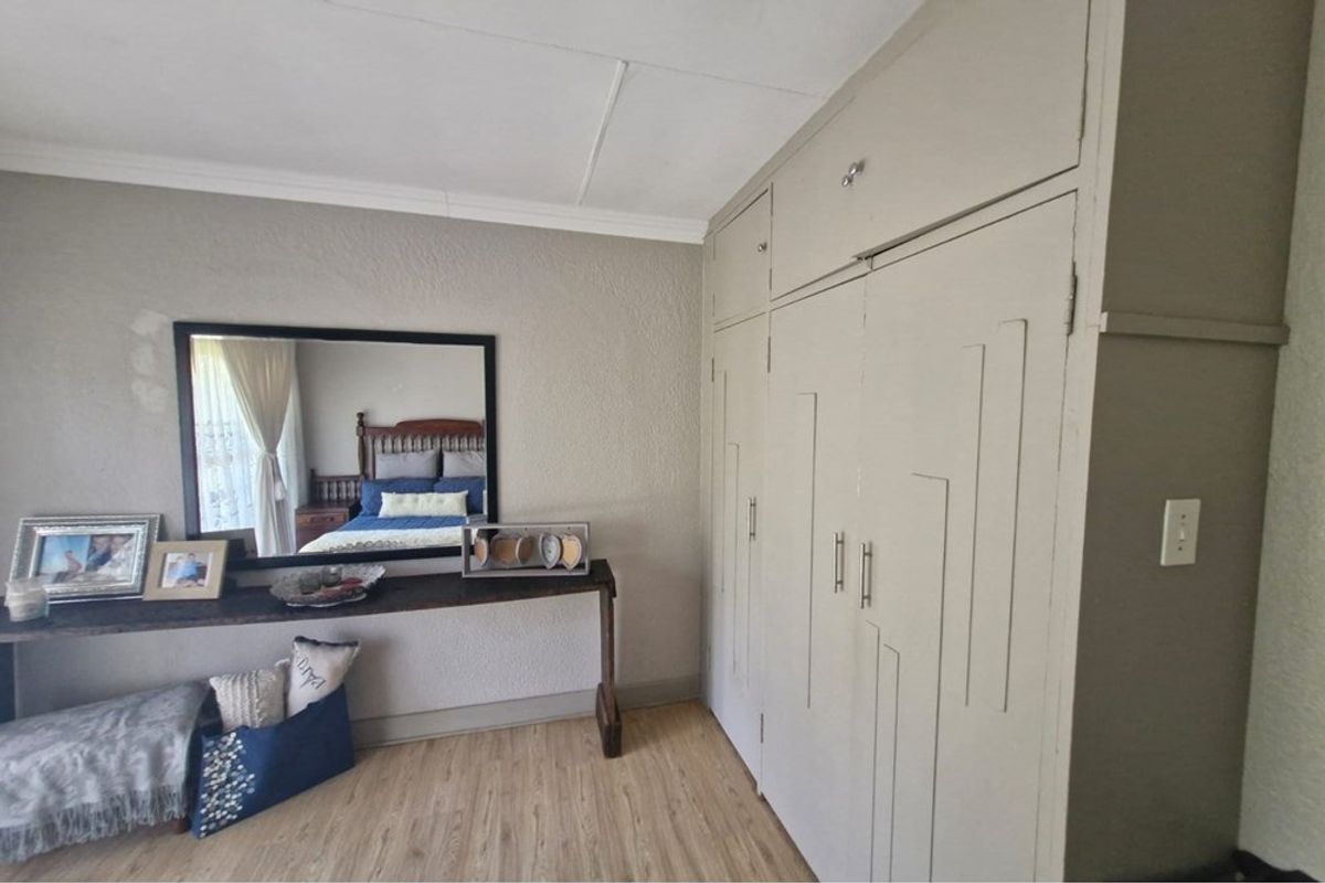 A bedroom featuring built-in cupboards with a neutral finish and light-toned laminate flooring.
