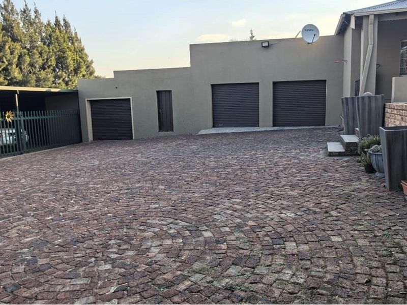 Exterior view of the property featuring a paved driveway, triple garage doors, and a covered carport area.