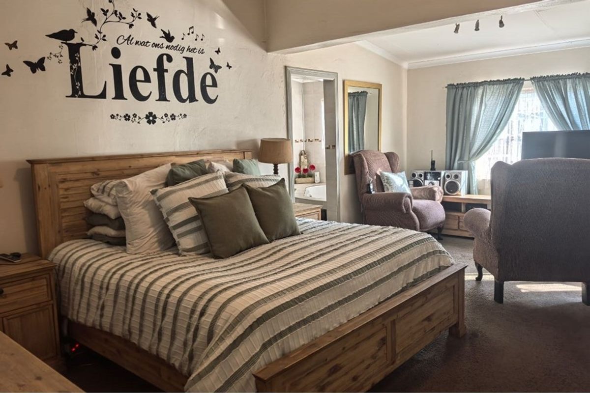 Spacious bedroom featuring an en-suite bathroom access, neutral wall tones, and large windows allowing for natural light.