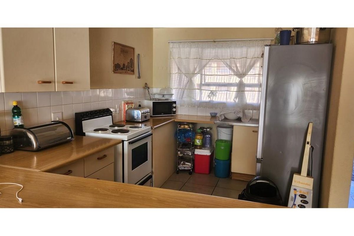 A compact kitchen featuring laminate countertops, built-in cabinetry, and a tiled splashback, offering a functional layout with potential for modern updates.