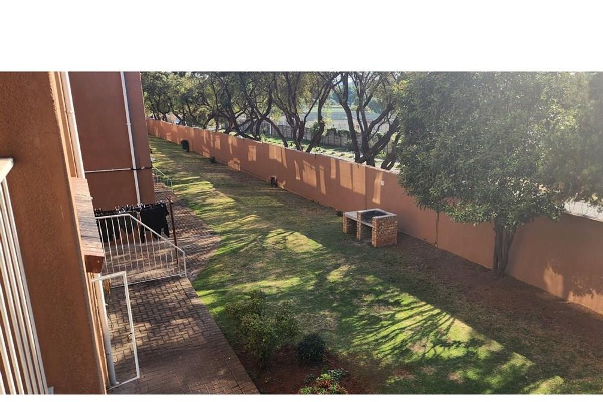 A private rear garden featuring a paved patio area, a built-in brick braai, and a perimeter wall, offering a functional outdoor space.