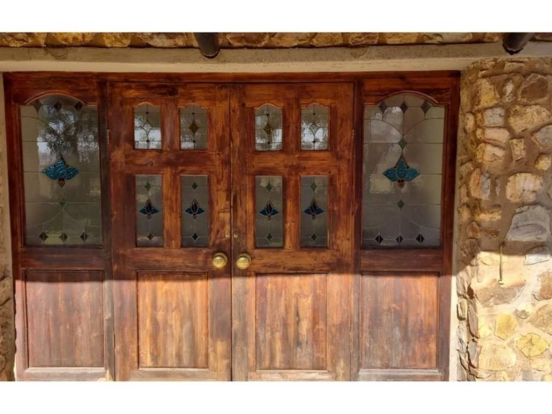 A rustic double entrance door featuring decorative stained glass panels set within a natural stone facade.