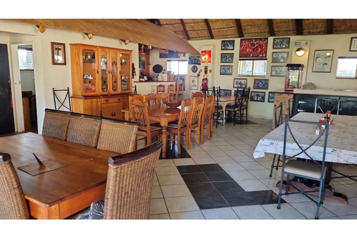 Spacious open-plan living and dining area featuring a traditional thatched roof, tiled flooring, and a built-in bar counter.