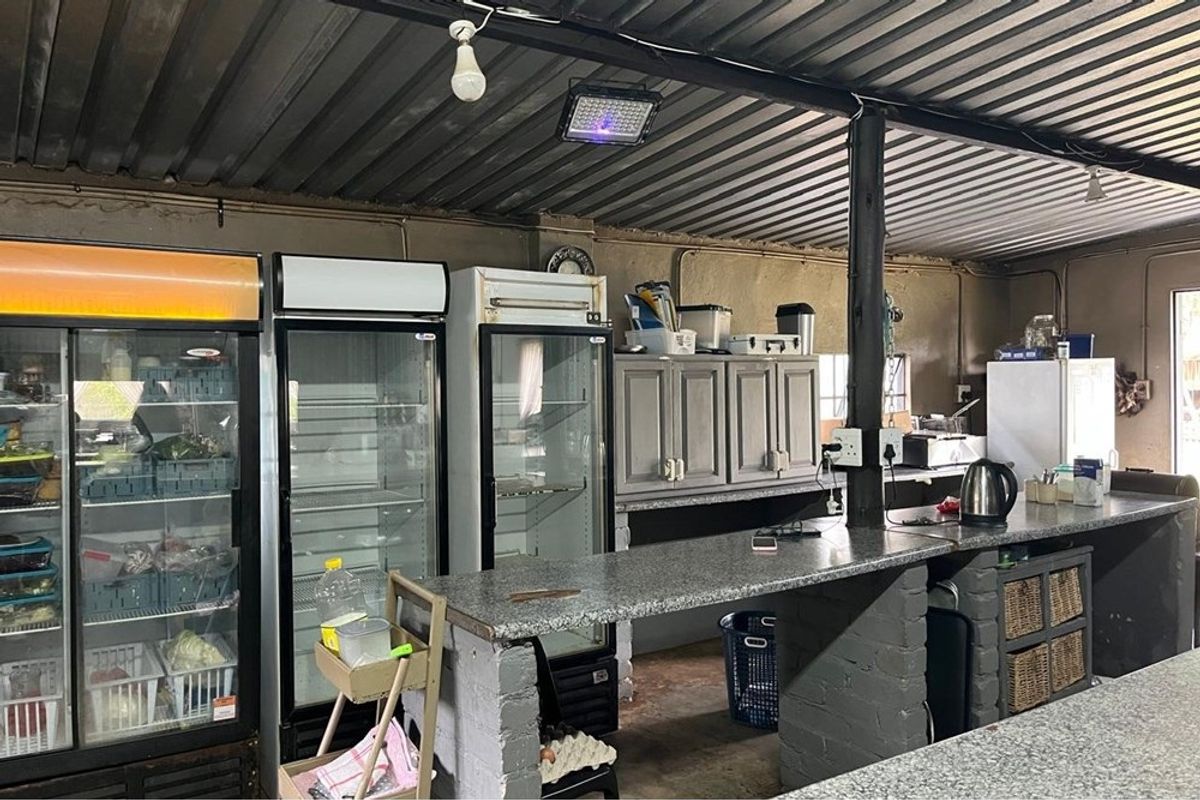 Industrial-style kitchen area featuring granite countertops, brick support pillars, and built-in cabinetry under a corrugated metal ceiling.