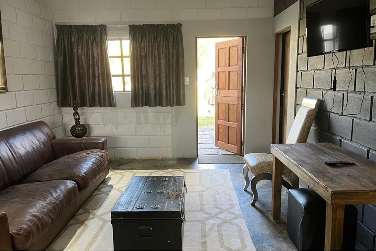 Living area featuring exposed concrete block walls, concrete flooring, and direct access to the exterior through a timber door.