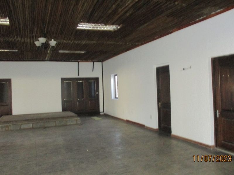 Spacious interior room featuring a timber ceiling, tiled flooring, and a raised platform, offering a blank canvas for renovation.