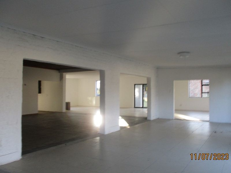 Spacious open-plan living area featuring tiled floors, painted brick walls, and multiple interconnected zones with natural light.