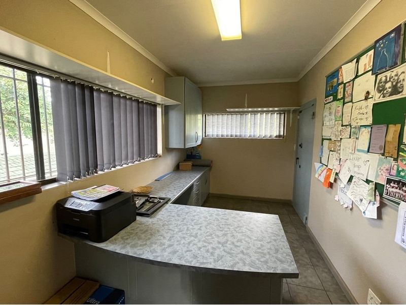 A functional scullery or utility space featuring built-in cabinetry, laminate countertops, and tiled flooring, providing practical workspace and storage.