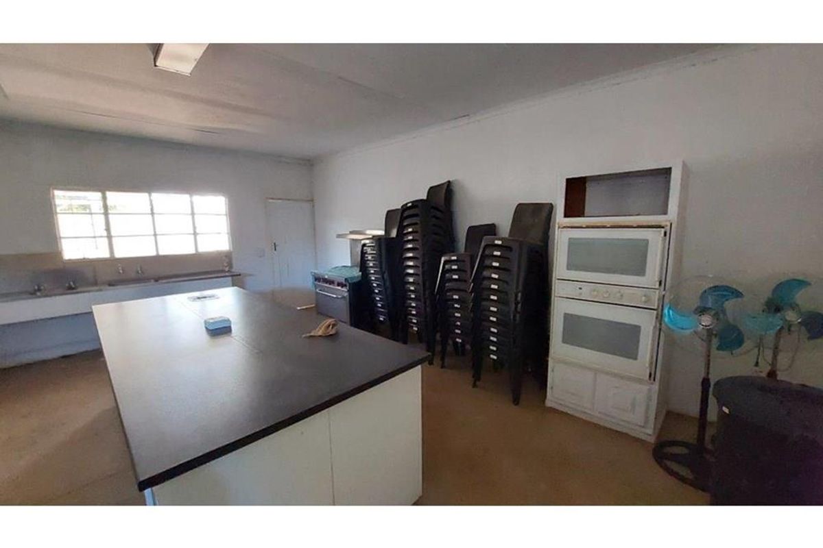 A spacious kitchen area featuring a central island, built-in double oven, and stainless steel sink, offering significant potential for modernization and renovation.