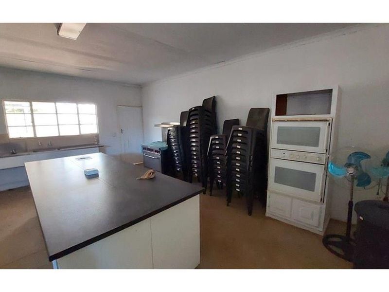 A spacious kitchen area featuring a central island, built-in double oven, and stainless steel sink, offering significant potential for modernization and renovation.