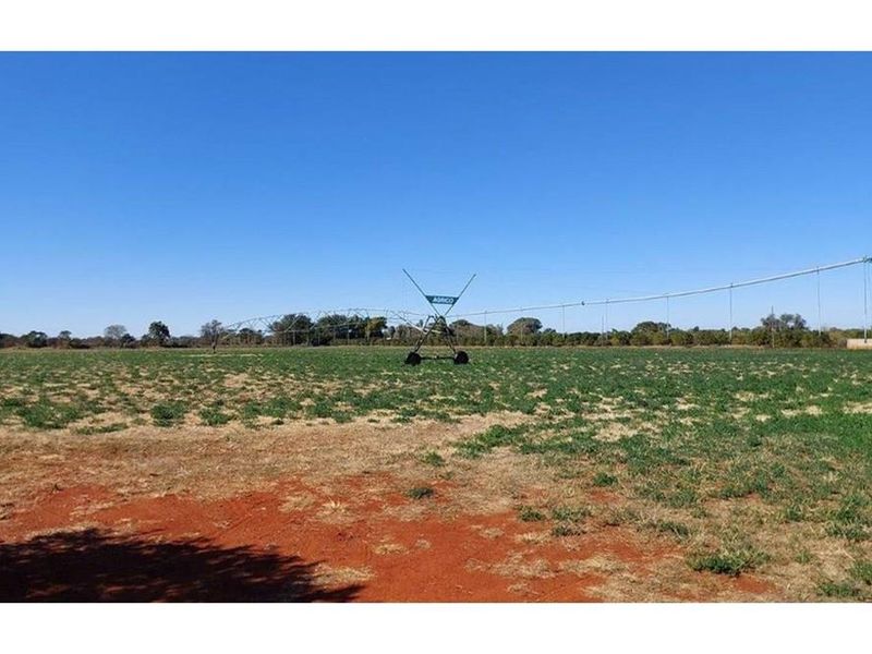 Expansive agricultural land featuring a functional center pivot irrigation system for crop cultivation.
