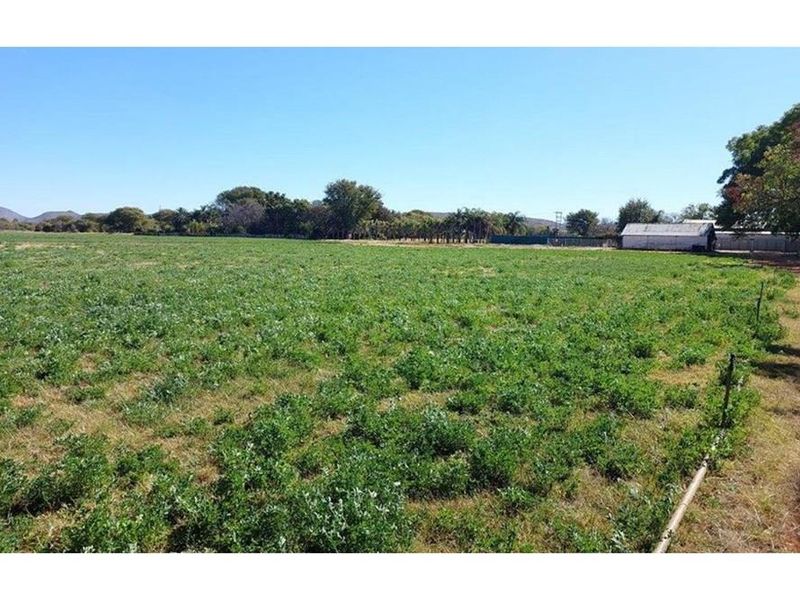 Expansive open agricultural land featuring wire fencing and a dirt access track, suitable for farming or development purposes.